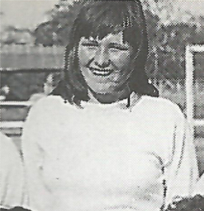 Smiling woman with shoulder-length dark hair in white t shirt