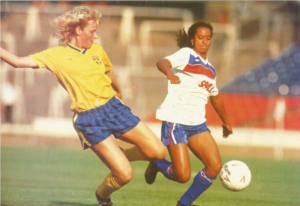 Two women footballers challenge for the ball in the bottom right of the picture