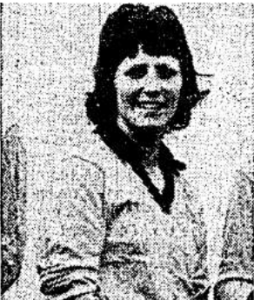 A greyscale head and shoulders portrait picture of a smiling dark haired young woman