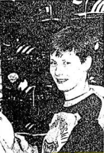 Black and white image of a woman with short, dark hair wearing a sweatshirt and holding a football